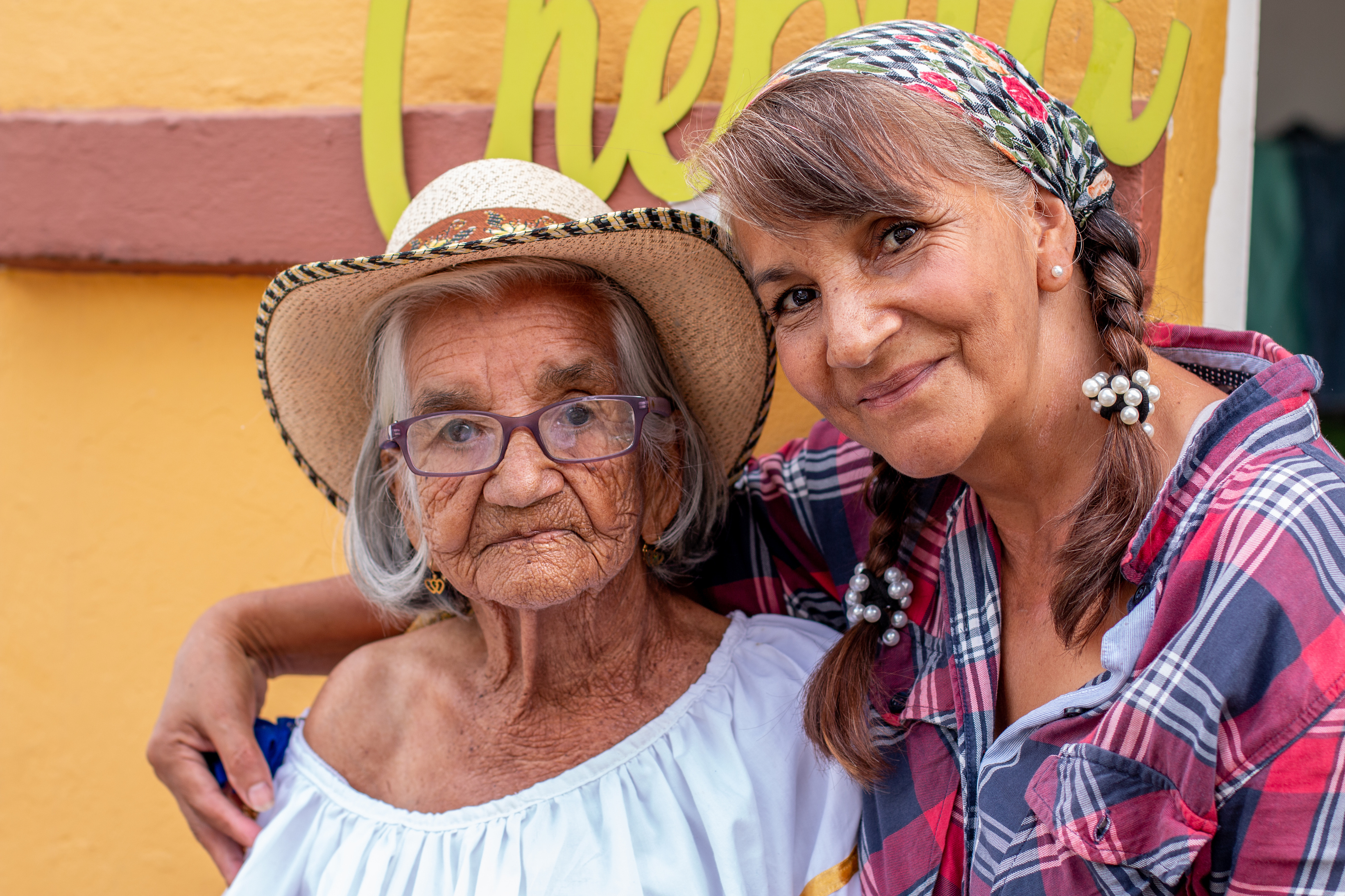 Portrait of old peasant woman with her smiling daughter, wearing typical Colombian clothes. Women with brown skin.